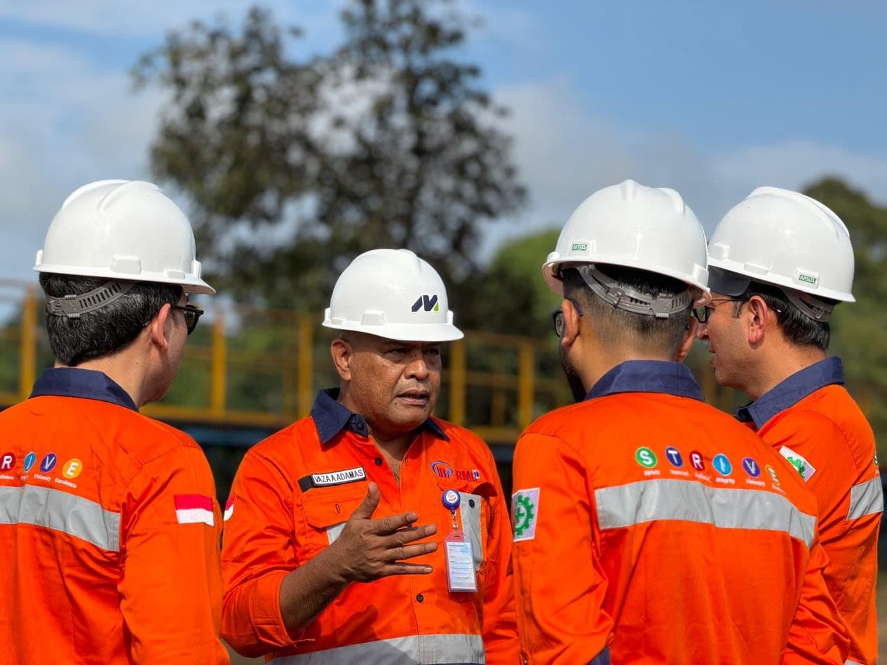 Colleagues talking on site, STRIVE values printed on their shirts
