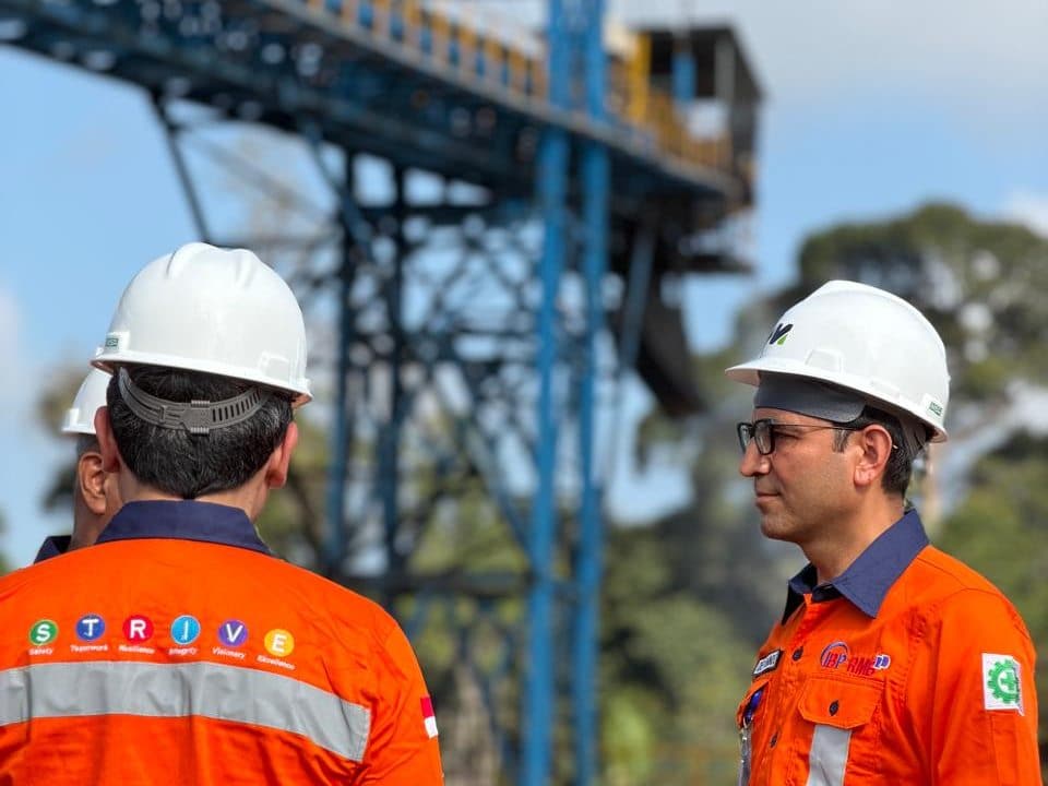 Two colleagues in hard hats beneath the barge loading conveyor tower